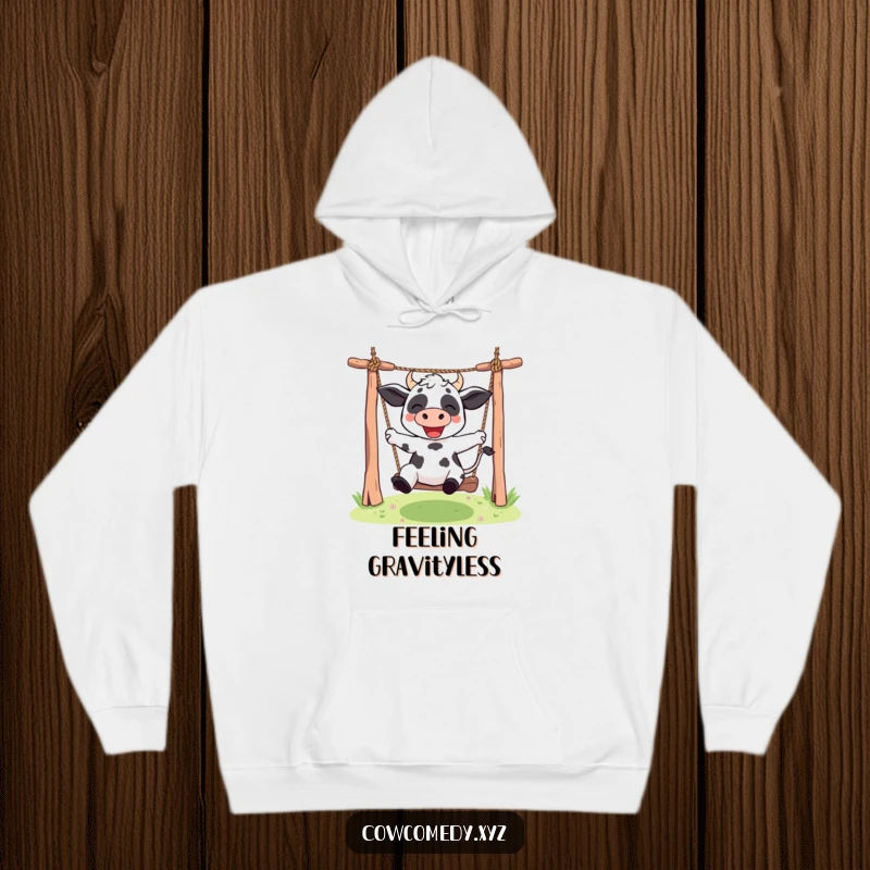 Funny Kawaii cow hoodie illustrating a cute character swinging energetically on a rope swing, embodying playful freedom and humor.