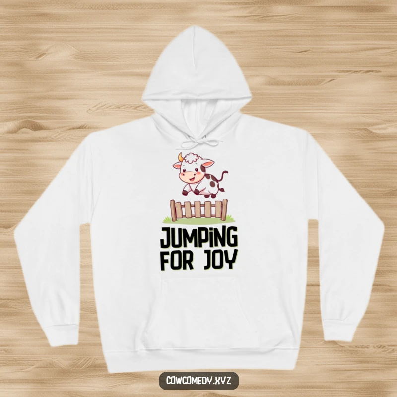 Funny hoodie design of a happy cow in mid-jump, leaping energetically over a small fence.