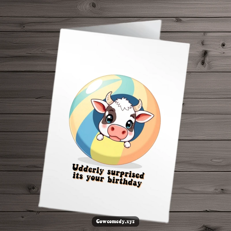 Funny Free Printable Birthday Card featuring a surprised cow peeking from behind a giant striped beach ball, ready for fun.