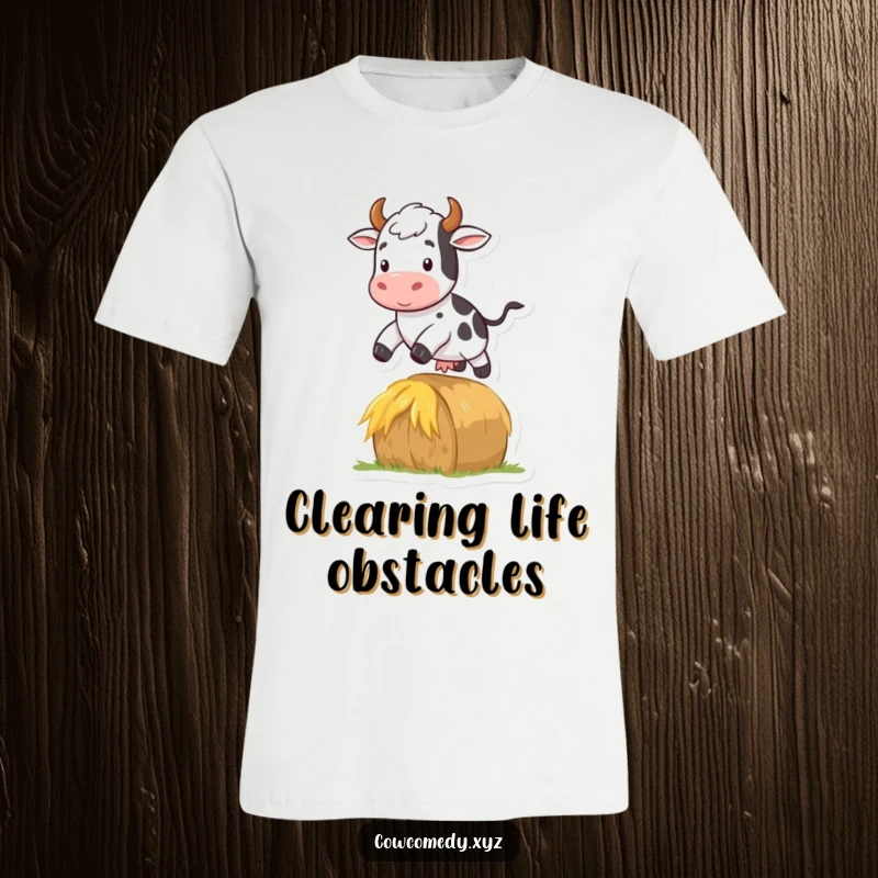 Funny t-shirt graphics of a cow joyfully jumping over a hay bale, showcasing agility and farm fun.