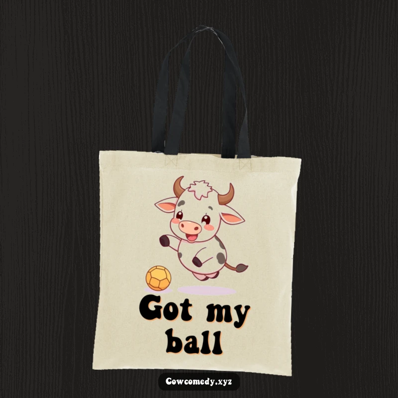 Funny tote bag featuring a happy cow gleefully kicking a small, round ball, perfect for errands.